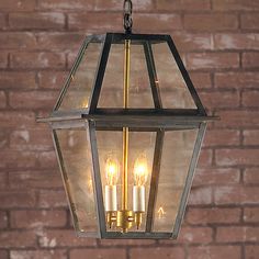 a lantern hanging from a brick wall with three lit candles in the center and one light on each side