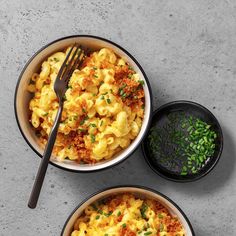 two bowls filled with macaroni and cheese on top of a gray countertop