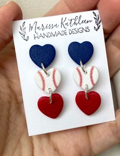 a pair of heart shaped baseball earrings with red, white and blue balls on them