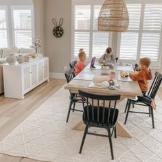 two children sitting at a table in the middle of a living room with white furniture