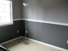 an empty room with a floor lamp in the corner