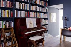 a piano in front of a bookshelf full of books