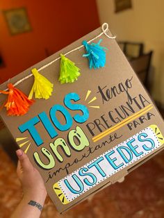 a person holding up a cardboard sign with tassels on it that reads tos uno preclunaria