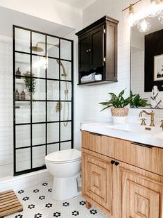 a bathroom with black and white tile, wood cabinets, and a glass shower door