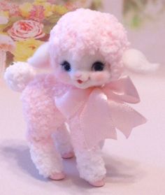 a small pink poodle with a bow on it's head and tail, standing in front of a flowered background