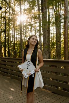 a woman standing on a wooden bridge holding a white piece of paper in her hand