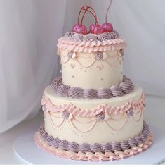 a three tiered cake with pink and purple icing, topped with cherries