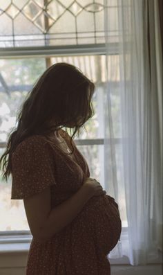 a pregnant woman standing in front of a window