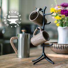 there is a coffee cup holder on the table with two mugs hanging from it