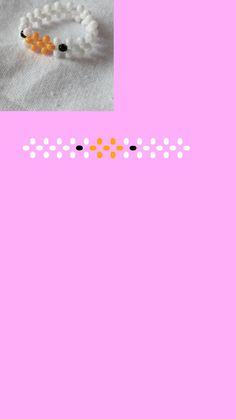 a pink background with an orange and black beaded bracelet next to it is a white flower