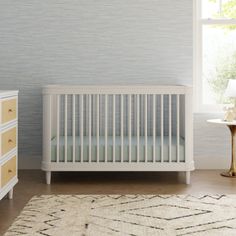 a white crib in a room with blue wallpaper and a rug on the floor