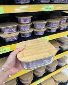 a person holding an ice cream container in front of some shelves