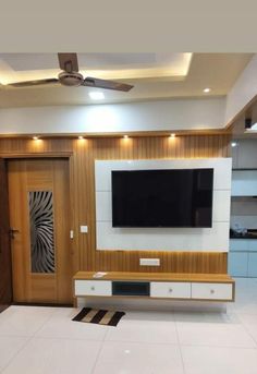 a living room with a flat screen tv mounted on the wall and white tile flooring