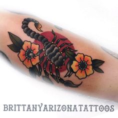 an arm tattoo with flowers and scorpion on it