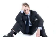 a man in a suit and tie sitting on the ground with his hands behind his head