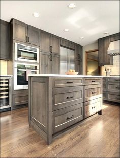 a large kitchen with wooden floors and gray cabinets