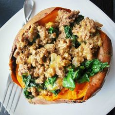 a white plate topped with a stuffed sweet potato covered in meat and vegetables next to a fork