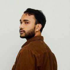 a man standing in front of a white wall with his head turned to the side