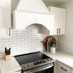 a stove top oven sitting inside of a kitchen next to white cabinets and counter tops