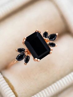 a ring with black stones on it sitting on top of a white cushioned surface