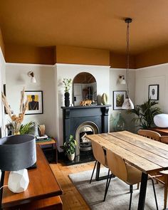 a living room filled with furniture and a fire place next to a table on top of a hard wood floor