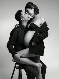 a man kissing a woman on the cheek while sitting in a chair next to him