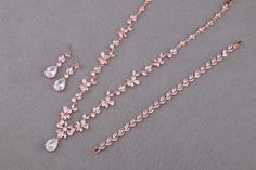 This Rose Gold Floral Bridal Jewelry Set is a perfect ensemble for the bride seeking a touch of boho charm on her special day. The set includes a chunky necklace, teardrop pendent choker, and a leaf bracelet, all adorned with sparkling cubic zirconia stones that catch the light beautifully. CZ NECKLACE: Necklace Length: approx 16 1/2 inches. Featuring a floral design that adds a touch of nature's elegance to your bridal look. Crafted with high-quality cubic zirconia stones and copper, this necklace is designed to sparkle under any light. CZ EARRINGS: These floral design earrings are a beautiful addition to the set, suitable for any occasion. The earring length is about 1 3/8" (3.5cm), with a bottom teardrop size of 1/2"H x 3/8"W (1.5cm x 1cm), offering a delicate balance of size and style. Festive Rose Gold Bridal Necklace For Wedding, Rose Gold Crystal Bridal Necklace, Delicate Rose Gold Cubic Zirconia Bridal Necklace, Formal Gold Stone-set Bridal Necklace, Luxury Hand-set Rose Gold Bridal Necklace, Rose Gold Bridal Jewelry Set, Gold Bridal Jewelry, Rose Gold Earrings Wedding, Crystal Bridal Jewelry Sets