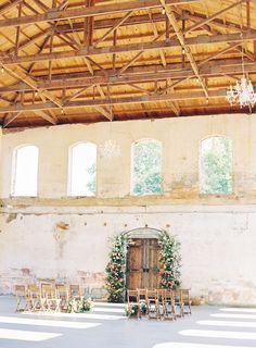 an indoor wedding venue with wooden chairs and chandelier