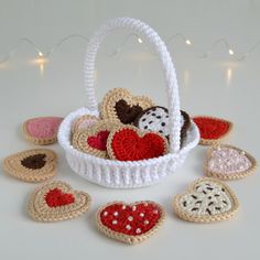 small crocheted hearts in a basket on a white table with string lights behind them