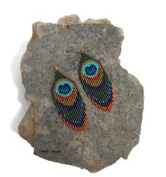 a pair of beaded earrings sitting on top of a rock