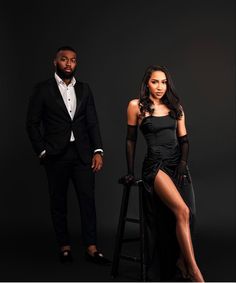 a man and woman in formal wear posing for the camera with one leg on a stool