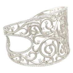 Cellini Jewelers lovely 18 karat white gold and diamond cuff bracelet. The very understated and elegant cuff is designed with a matte finished 18 karat white gold. The center is a swirl lace pattern tipped with round brilliant diamonds . A single row of round brilliant diamonds borders the entire bracelet. At the widest the cuff measures 1-5/8" and tapers to the back at approximately 1". The inside width of the cuff is 2-1/4". Total diamond weight 405 = 4.90 carats Lace Cuff Bracelet, Guo Pei, Diamond Cuff Bracelet, Lace Cuffs, Lace Pattern, Metal Jewelry, White Gold Diamonds, Round Brilliant, Cuff Bracelet