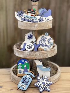 three tiered tray with decorated cookies on top of it and snowflakes in the bottom