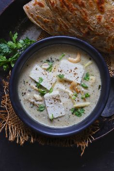 paneer in white gravy served in a black bowl with garnish