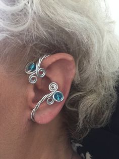 a close up of a person wearing some kind of ear cuff with blue stones on it