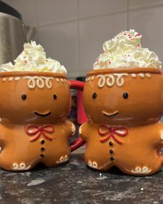 two ceramic gingerbread men with whipped cream on their heads sitting next to each other