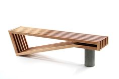 a wooden bench sitting on top of a white floor next to a metal pole with two legs