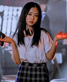 a woman with long black hair wearing headphones and holding her hands out in front of her