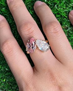 a woman's hand with a pink and white diamond ring on top of it