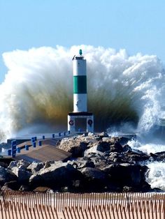 a large wave crashing over a light house