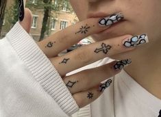 a woman with black and white nail art on her nails holding up her hand to her face