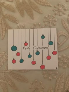 a card with christmas balls hanging from it's strings and merry lettering on the front