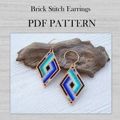 a pair of beaded earrings sitting on top of a piece of wood next to a rock