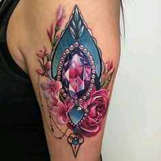 a woman with a tattoo on her arm has a pink flower and blue diamond in the center