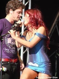 a man and woman standing next to each other at a music festival with microphones in their hands