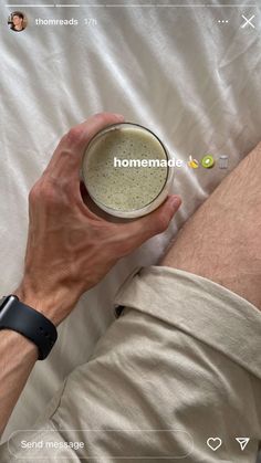 a man laying in bed holding a cup with the word homemade written on it's side