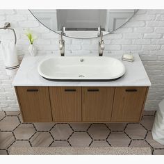 a white sink sitting under a mirror next to a bath tub in a tiled bathroom