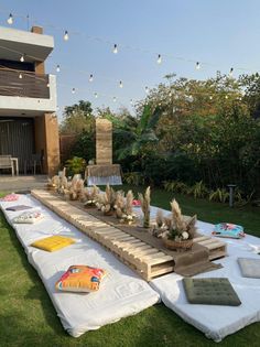 a long table with plants on it in the middle of some grass and string lights