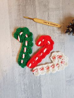 two crocheted christmas decorations next to a pine cone with a knitting needle on it