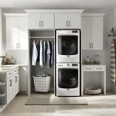 a washer and dryer in a small room with white cupboards, cabinets, and drawers